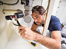 Plumber Repairing A Kitchen Sink Drain With A Wrench.